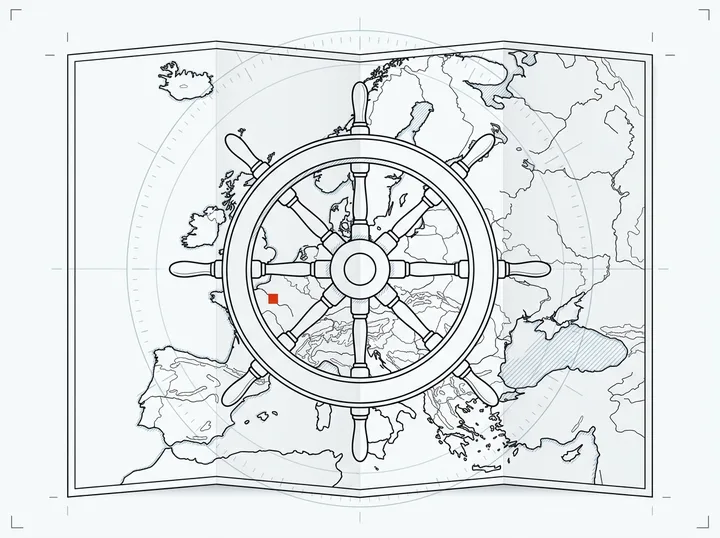 A ship's helm wheel over a folded map of Europe